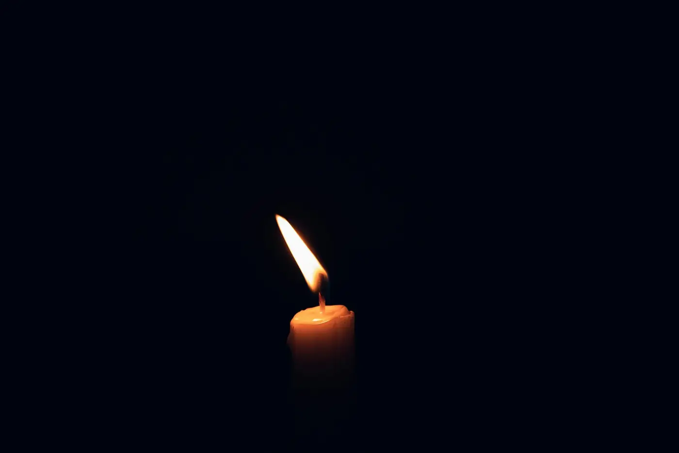 A single candle flame in the dark